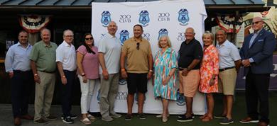 County officials, 200 club member and others in front of a 200 Club step &amp; repeat