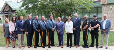 local officials, county officials, police officers and others in a group photo in front of the elementary school